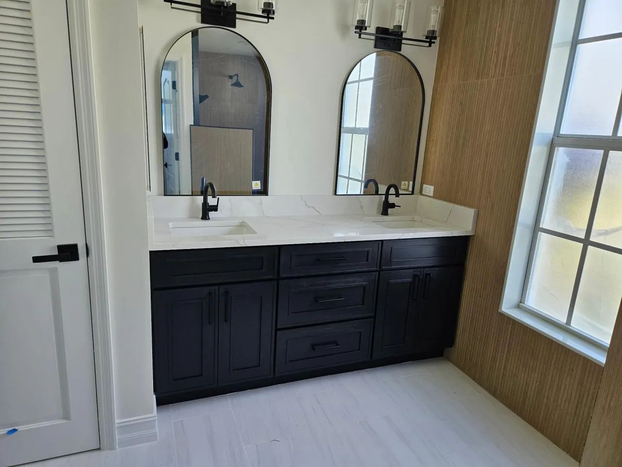 Double vanity with arched mirrors and wood-slat accent wall